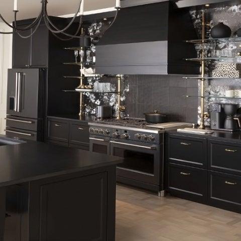 Luxury kitchen featuring a professional range and stylish black cabinetry with overhead shelves.