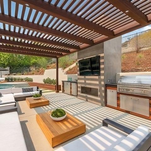 Outdoor kitchen area with a built-in BBQ grill, dining space, and a pergola for entertaining.